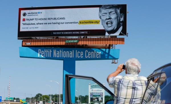 Man photographing a billboard of Do<em></em>nald Trump launched by the Democratic Natio<em></em>nal Committee in Milwaukee, Wisconsin.
