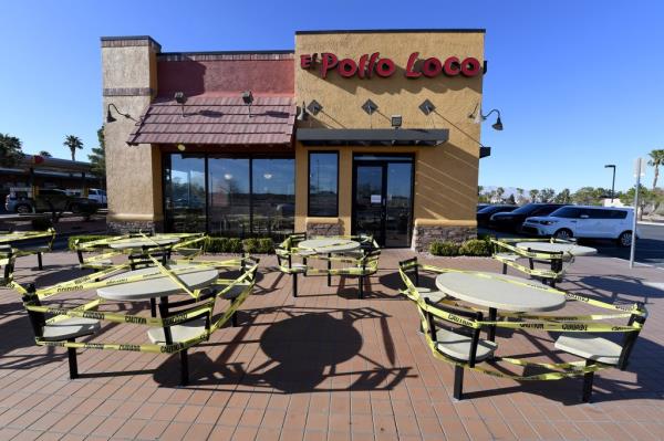 Tables and chairs in front of El Pollo Loco restaurant, blocked off with caution tape, due to coro<em></em>navirus pandemic.
