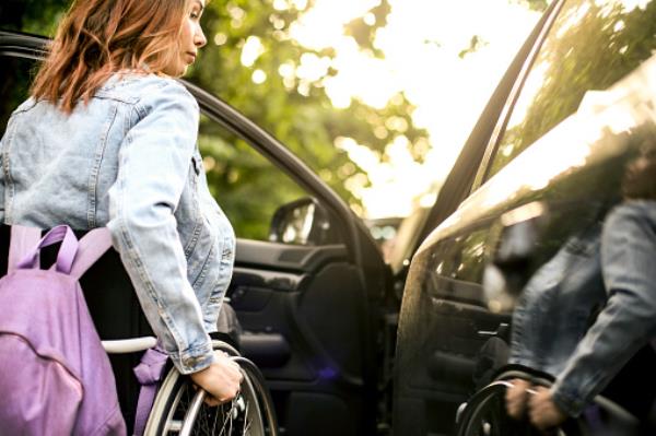 Disabled young woman getting in a car