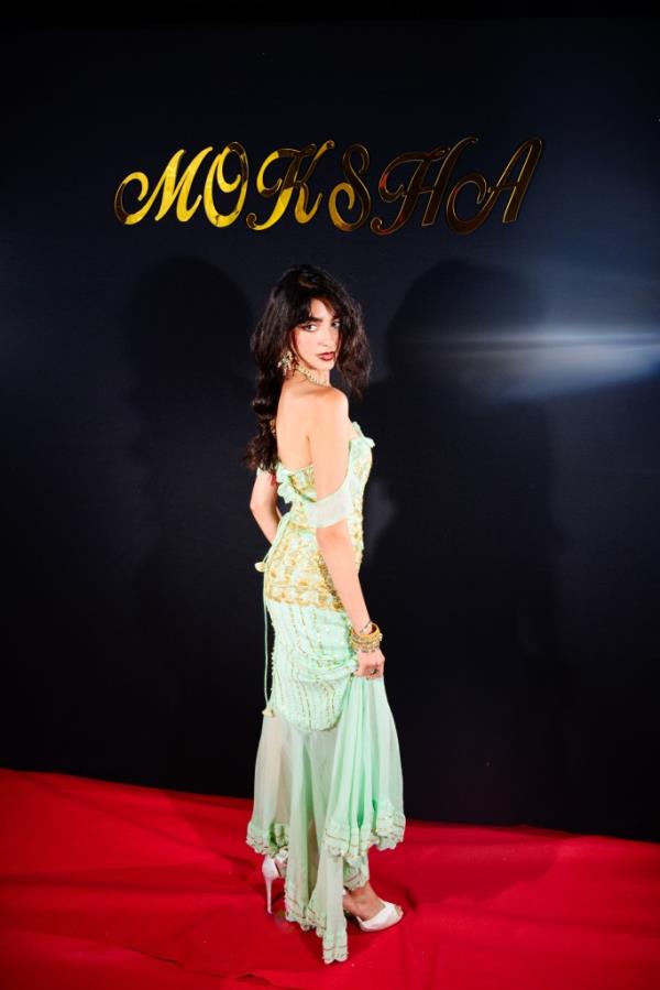 Woman in long green dress standing on a red carpet
