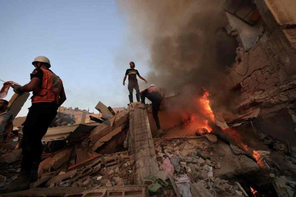 Palestinian rescuers attempt to put out a fire as they stand on the rubble of a collapsed building following a strike by the Israeli military on Khan Yunis in Southern Gaza.
