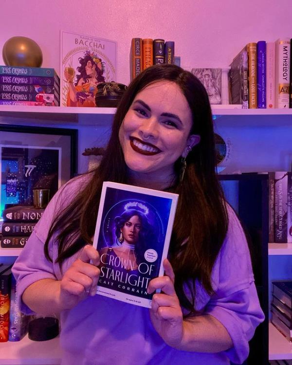 Cait Corrain is pictured holding up her book 