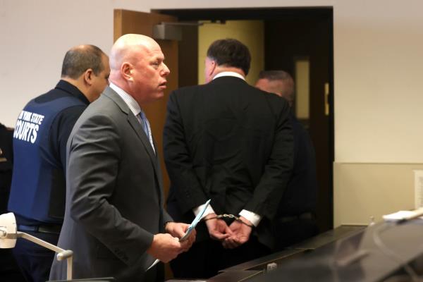 Man in handcuffs escorted out of court by attorney and guard.