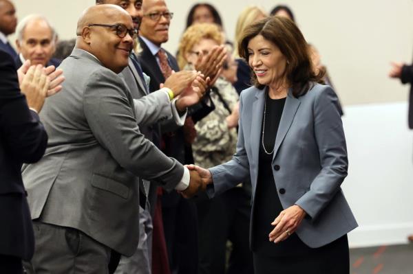 Governor Kathy Hochul shaking hands with Assemblyman Edward Gibbs at NYU Law School before signing a voting rights bill