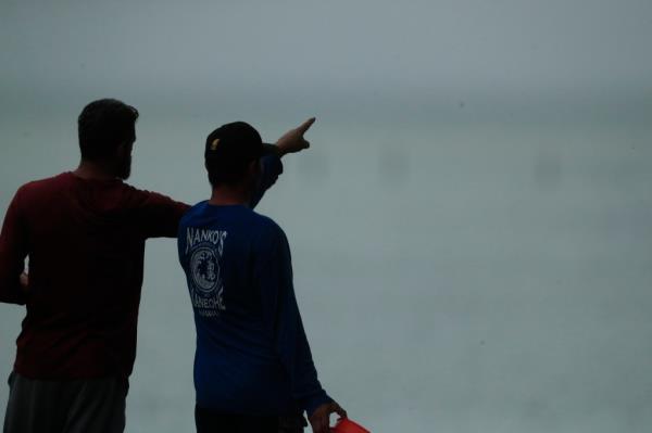 Residents look at a downed U.S. Navy aircraft in Kaneohe Bay