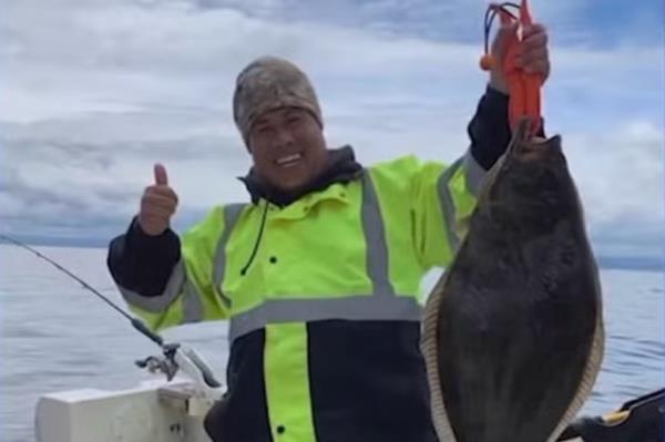 Prasong Khammoungkhoune holds up a fish on a boat.