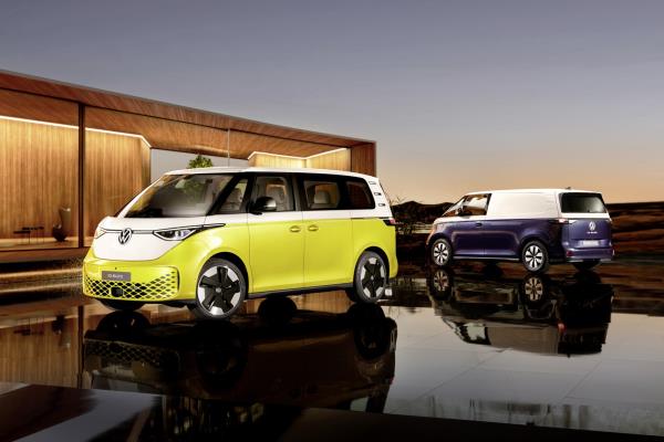 Two Volkswagen ID Buzz electric vans parked in front of house at dusk