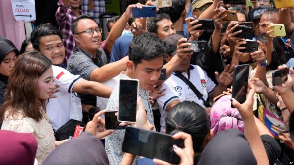 Vice presidential candidate and eldest son of Indo<em></em>nesian President Joko Widodo, Gibran Rakabuming Raka, center, talks to his supporters after voting during the election at a polling station in Solo, Indonesia, Feb. 14, 2024.
